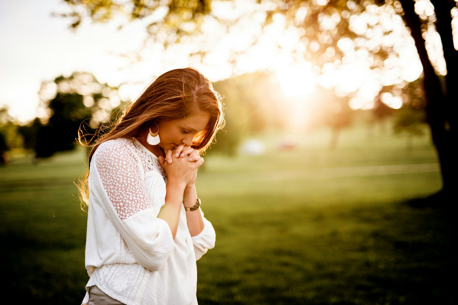 woman praying beside tree