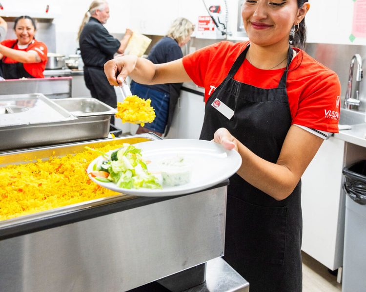 Volunteer serving a community meal at The Compass Kitchen in Mississauga